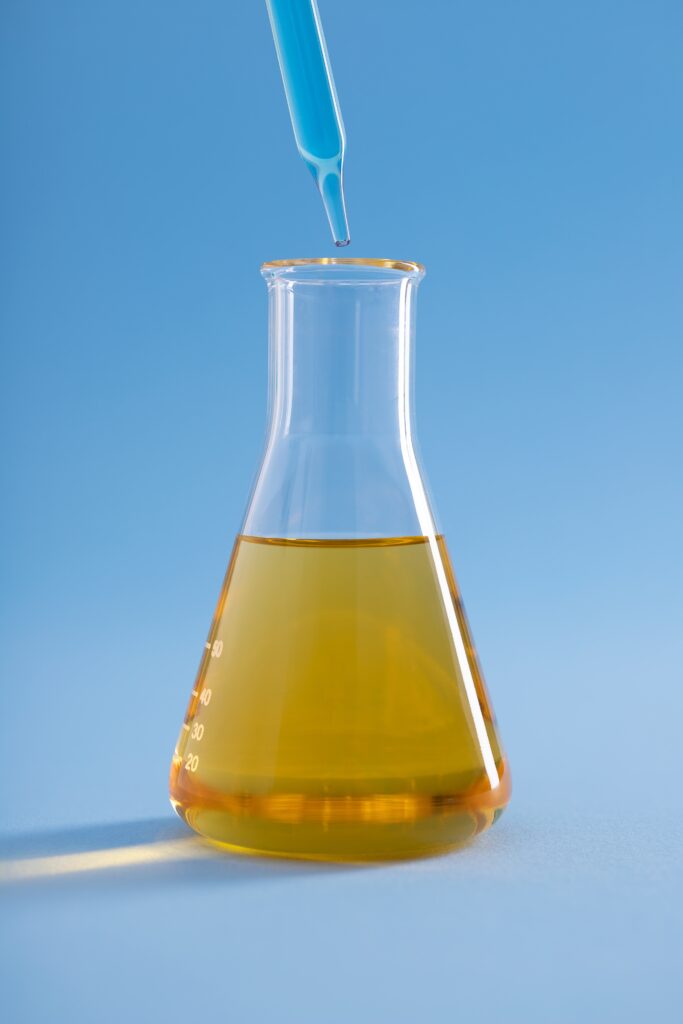 vertical closeup dropper with blue liquid erlenmeyer flask yellow liquid blue surface R G Polymers